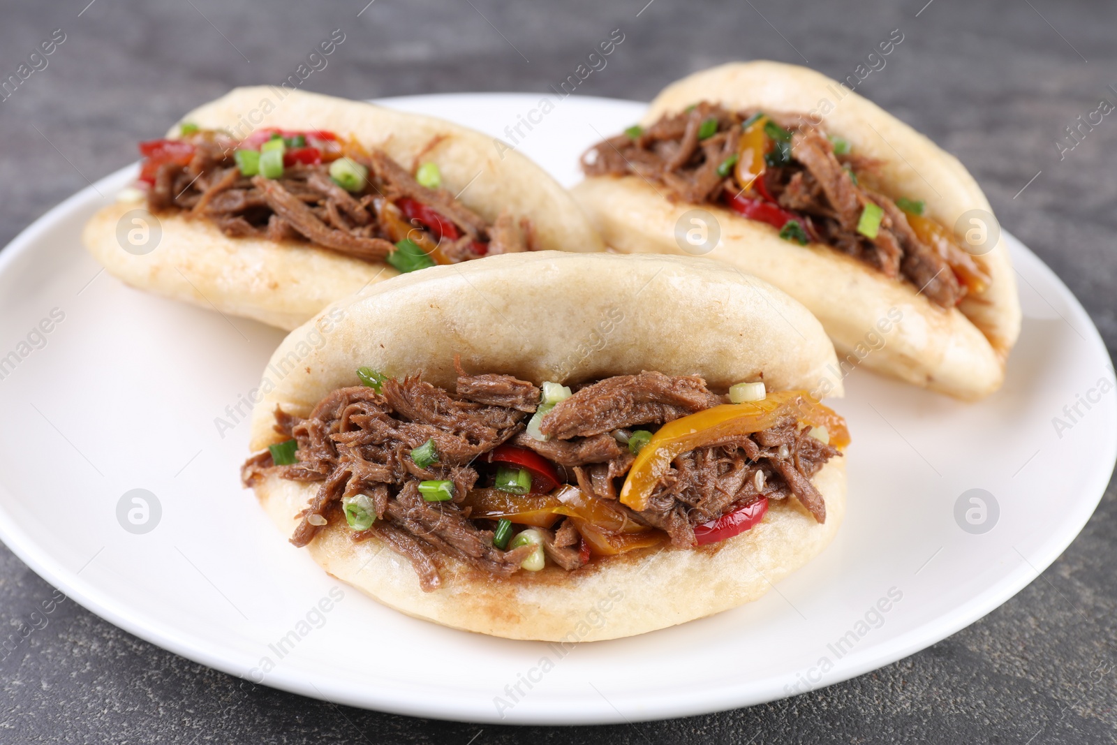 Photo of Delicious gua bao in plate on grey table, closeup