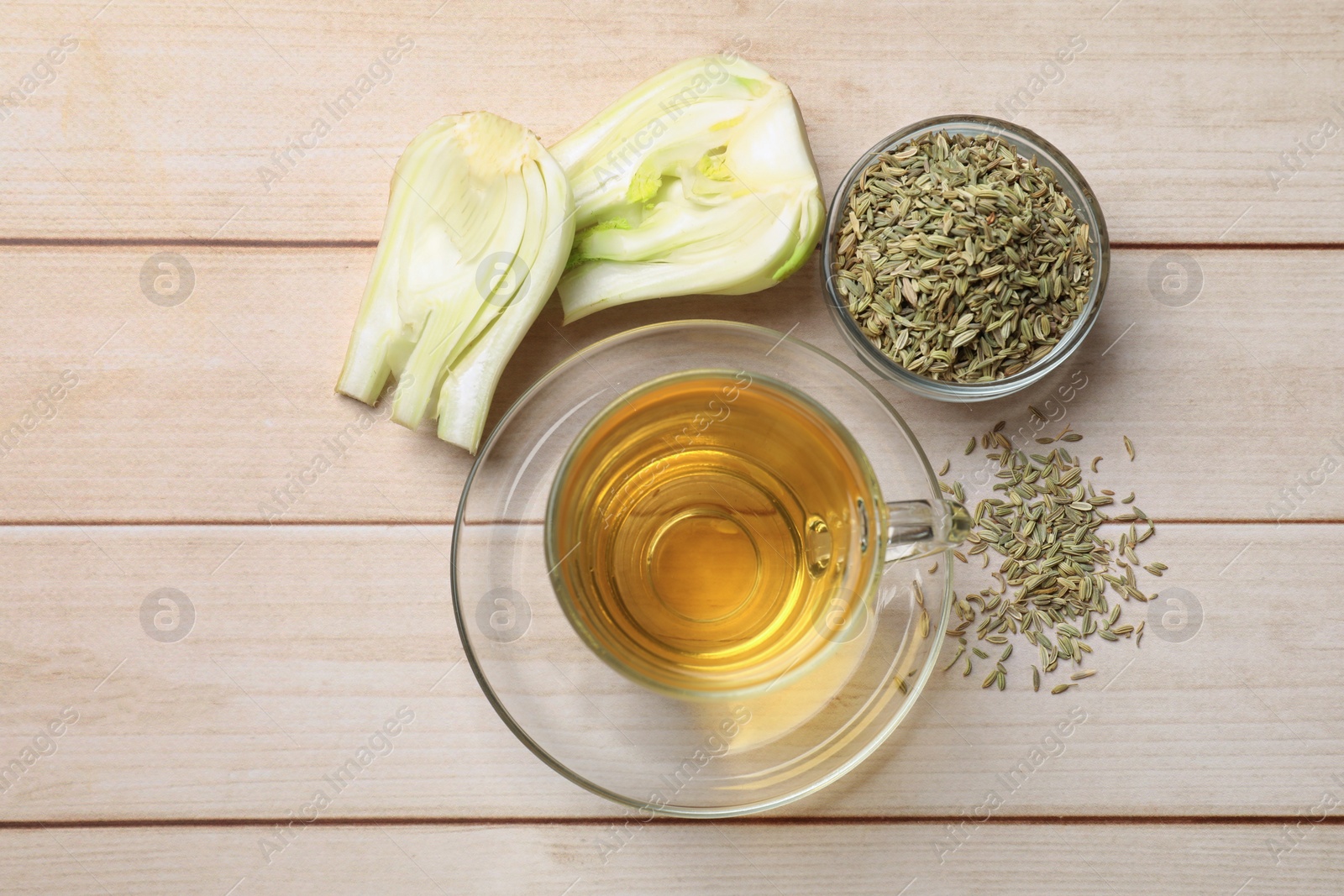 Photo of Aromatic fennel tea, seeds and fresh vegetable on wooden table, flat lay