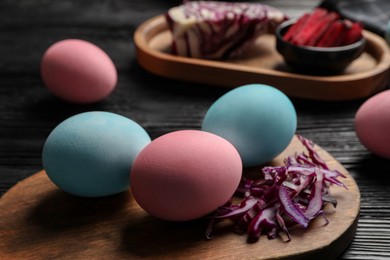 Photo of Naturally painted Easter eggs on black wooden table, closeup. Red cabbage used for coloring