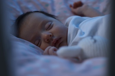 Cute newborn baby sleeping in crib at night, closeup