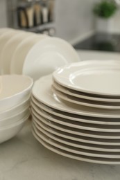 Photo of Clean plates and bowls on white marble table in kitchen