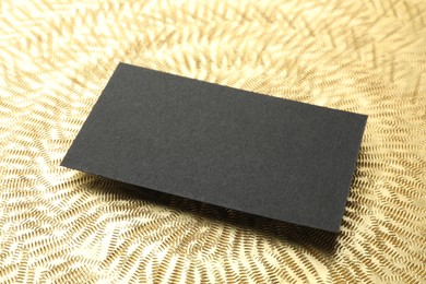 Blank business card on golden background, closeup. Mockup for design