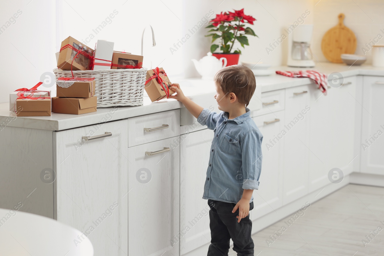 Photo of Little boy with Christmas gifts at home. Advent calendar in basket