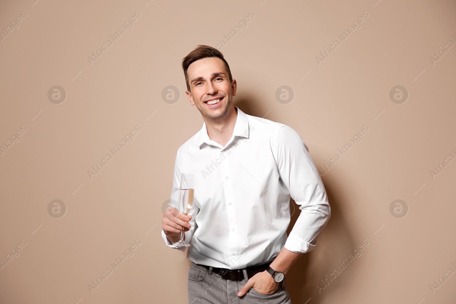 Photo of Handsome man with glass of champagne on color background