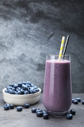 Glass of blueberry smoothie with fresh berries on grey table