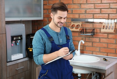 Photo of Male plumber with clipboard in kitchen. Repair service