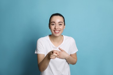 Photo of Beautiful young woman laughing on light blue background. Funny joke