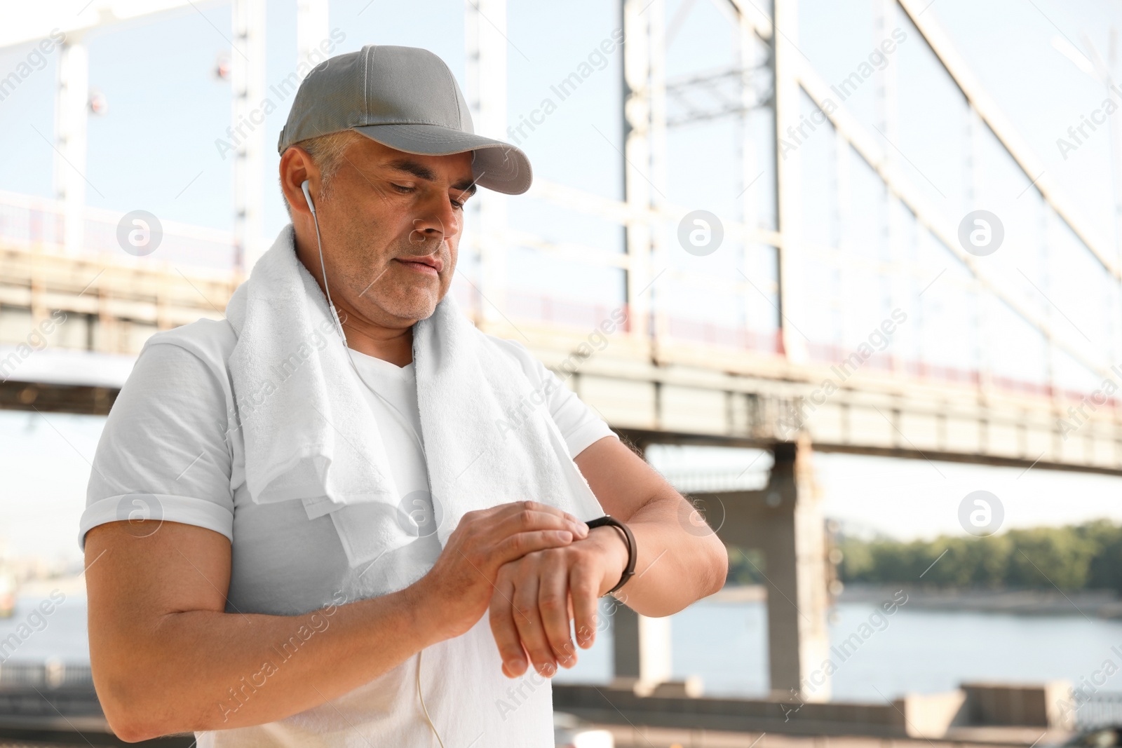 Photo of Handsome mature man looking at fitness tracker outdoors, space for text. Healthy lifestyle