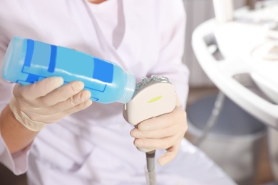 Photo of Sonographer covering ultrasound machine probe with gel in clinic, closeup