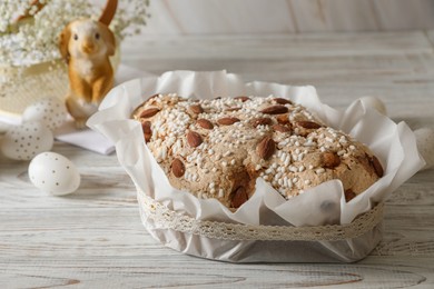 Photo of Delicious Italian Easter dove cake (traditional Colomba di Pasqua) and decorated eggs on white wooden table