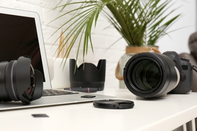 Laptop and professional photographer's equipment on table indoors