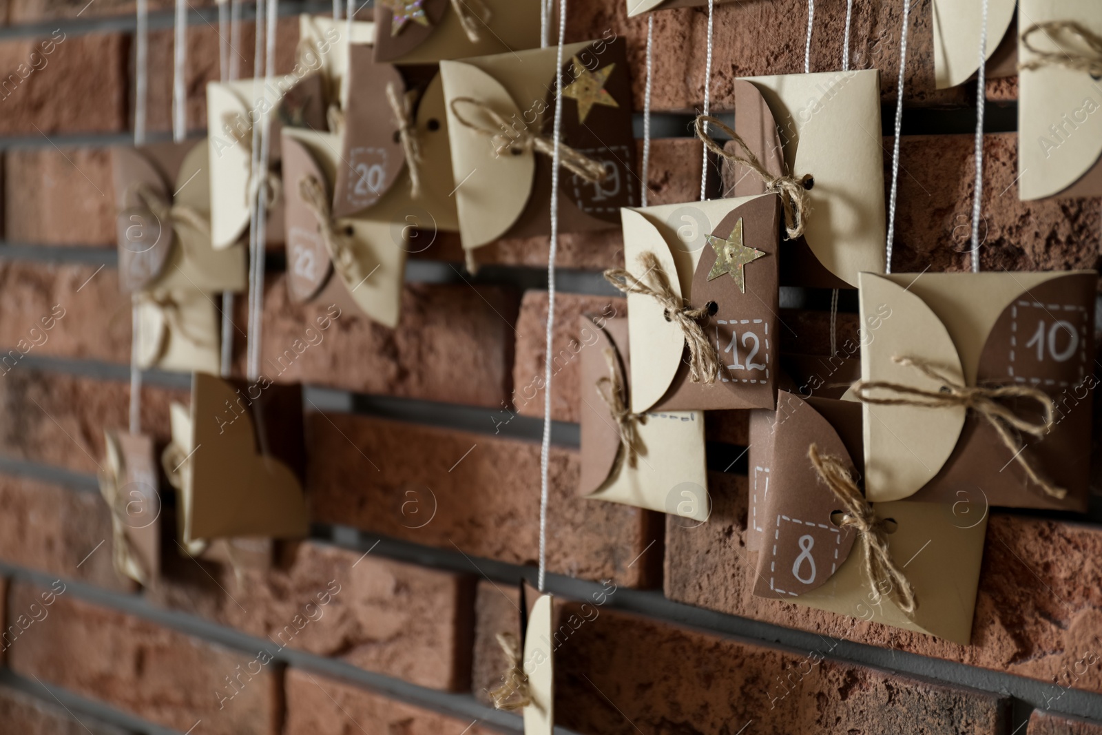 Photo of Christmas advent calendar hanging on brick wall indoors