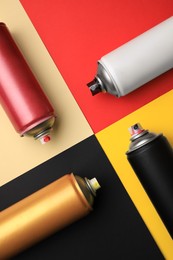 Cans of different graffiti spray paints on color background, flat lay