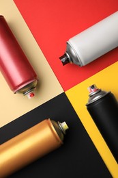 Photo of Cans of different graffiti spray paints on color background, flat lay