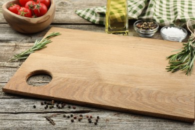 Photo of Cutting board, rosemary, oil and pepper on wooden table. Space for text