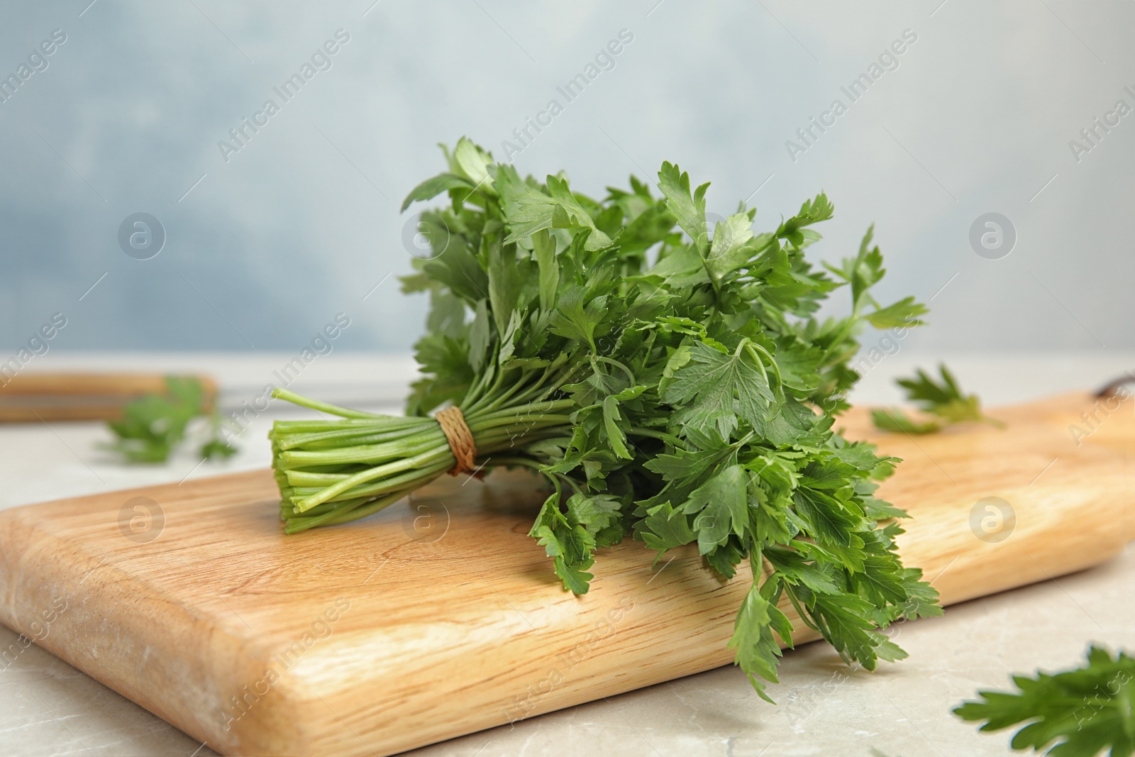 Photo of Wooden board with fresh green parsley on table, closeup