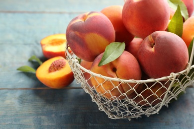 Fresh sweet peaches in metal basket on wooden table, closeup