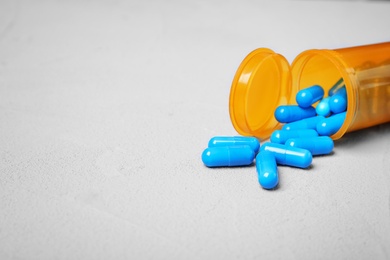 Photo of Container with blue capsules on grey background