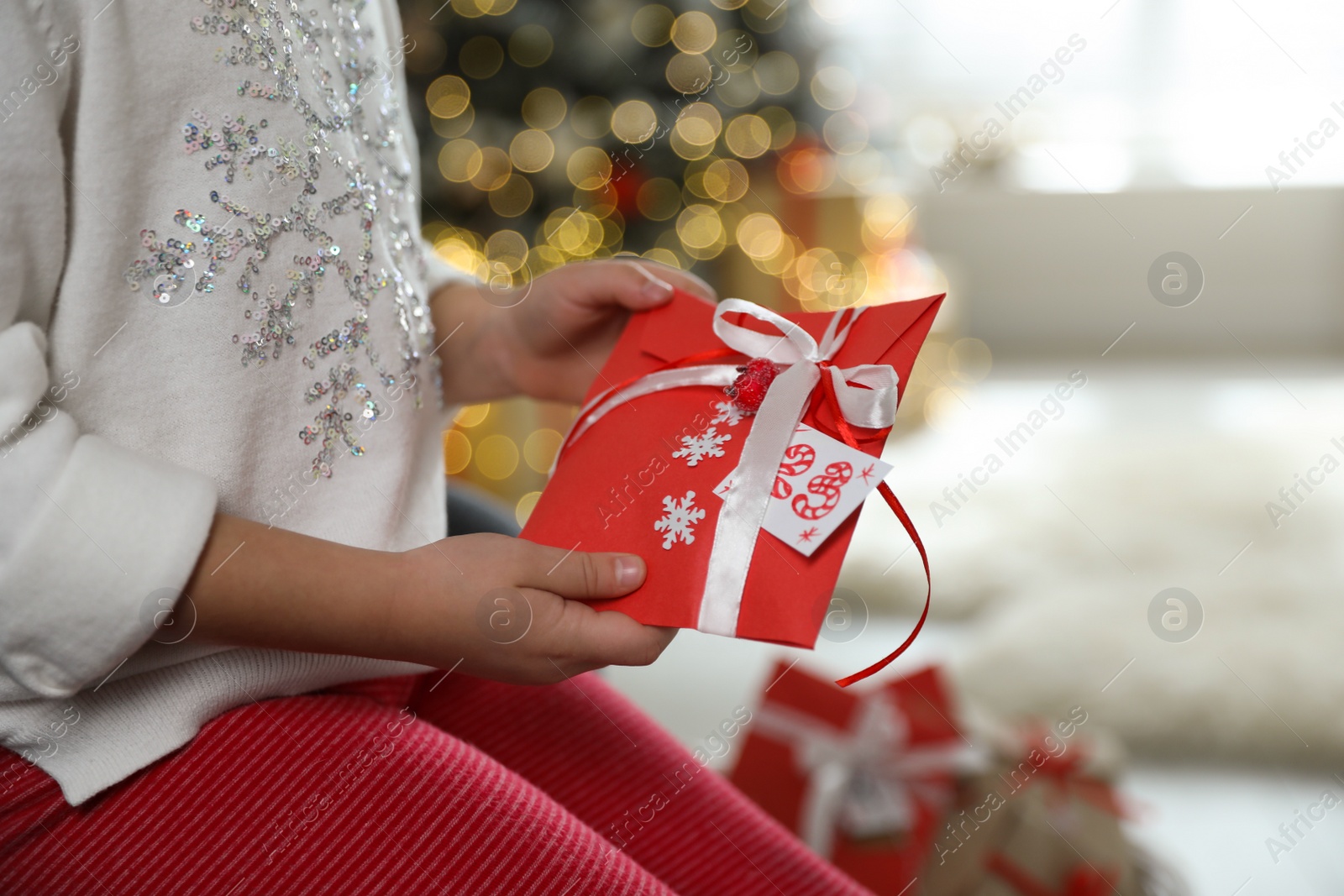 Photo of Little girl with gift from Christmas advent calendar at home, closeup