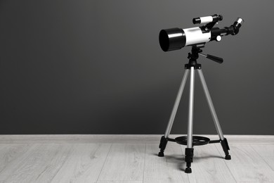 Photo of Tripod with modern telescope near grey wall. Space for text