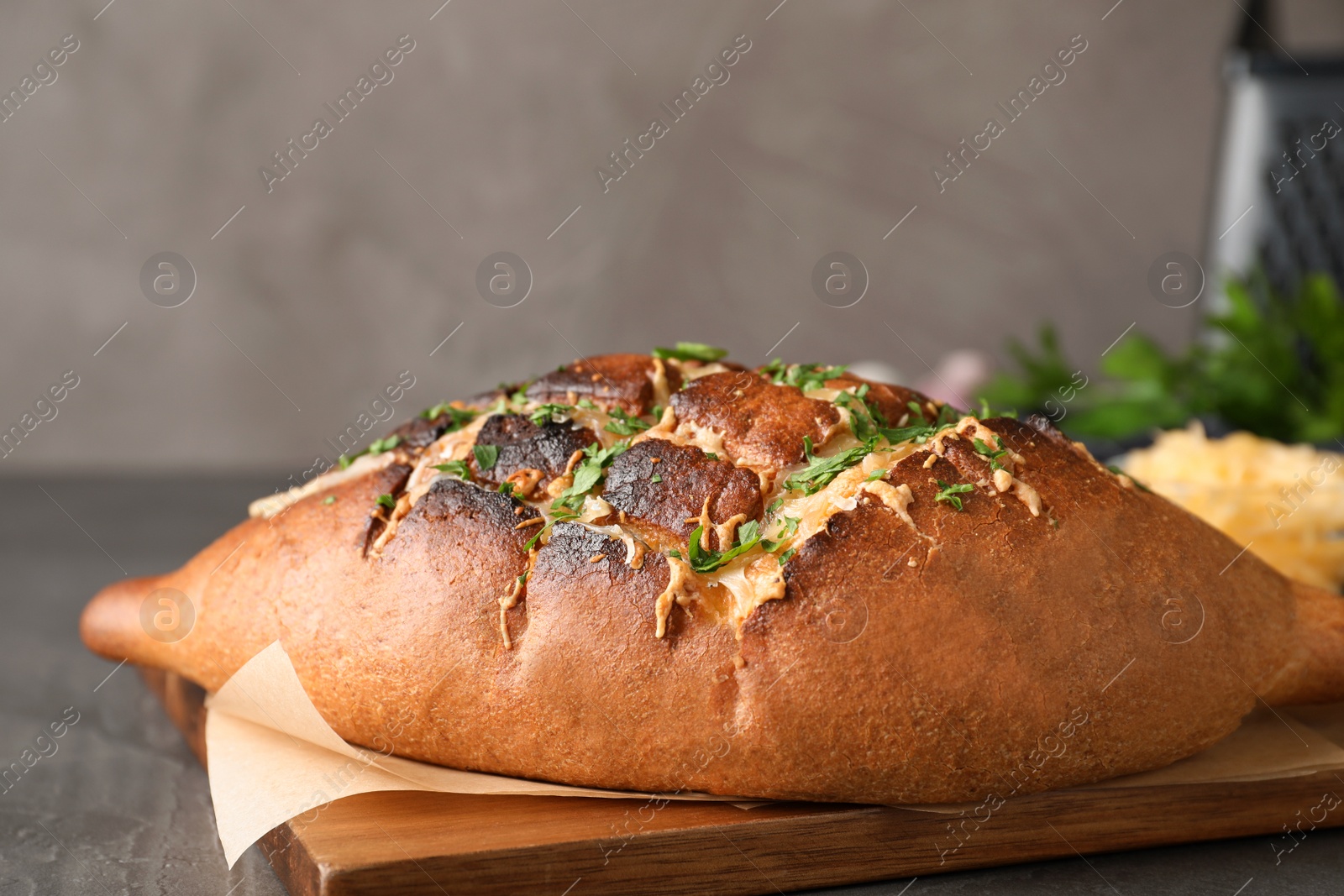 Photo of Delicious homemade garlic bread with herbs and cheese on grey table