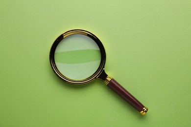 Photo of Magnifying glass on green background, top view