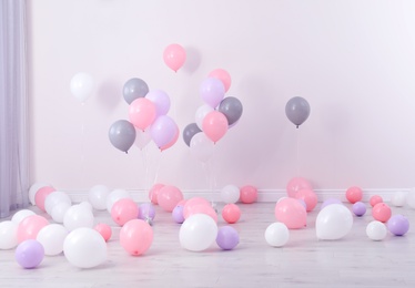 Room decorated with colorful balloons near wall