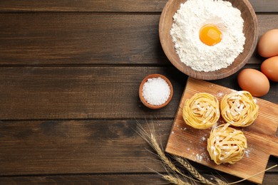 Raw noodles and ingredients on wooden table, flat lay. Space for text