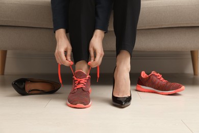 Photo of Woman changing shoes on sofa in office, closeup