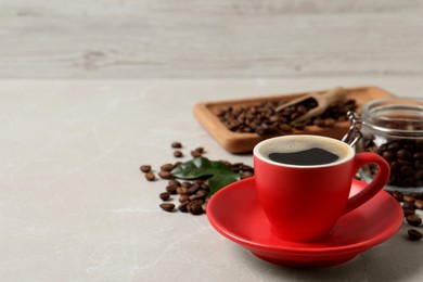 Photo of Cup of aromatic hot coffee and beans on light grey table, space for text