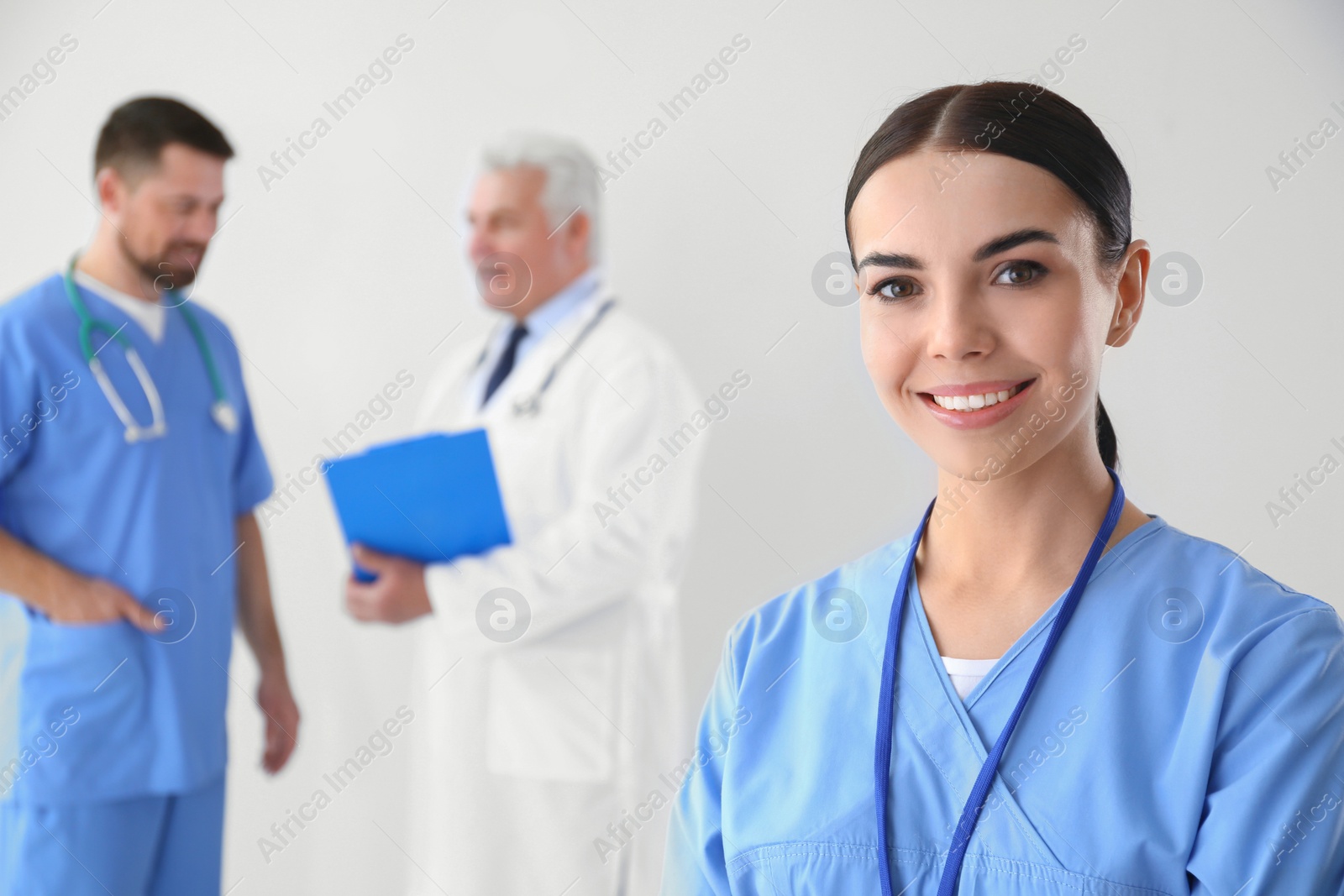 Photo of Young doctor with colleagues on light background