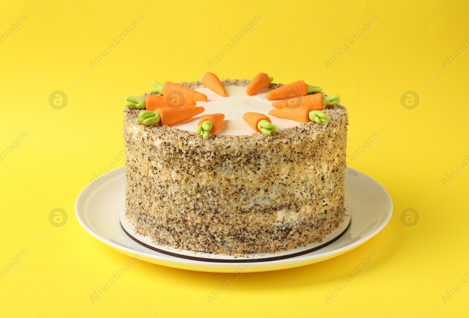 Photo of Dish with tasty carrot cake on yellow background