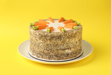 Dish with tasty carrot cake on yellow background