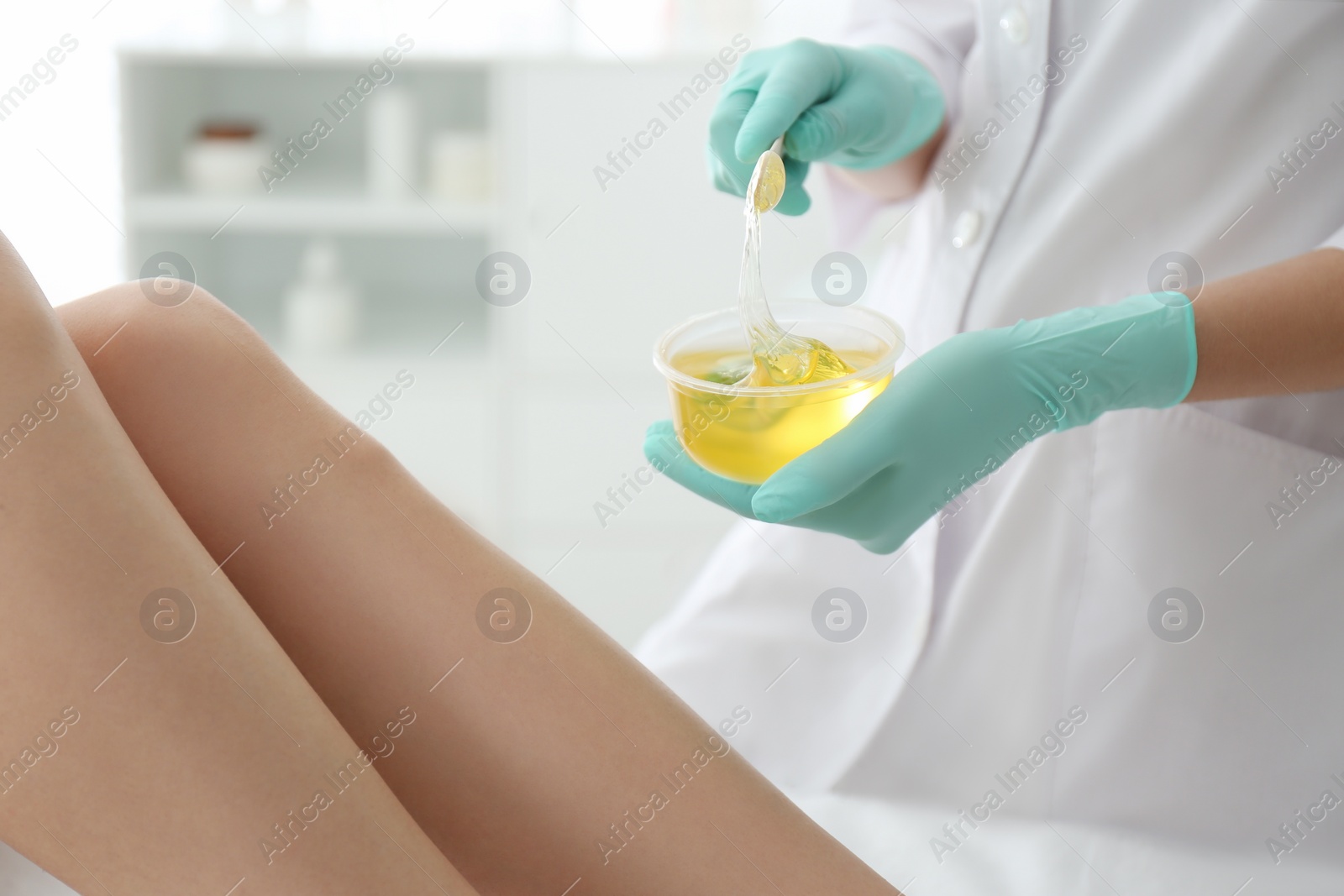 Photo of Woman getting wax epilation of legs in salon, closeup