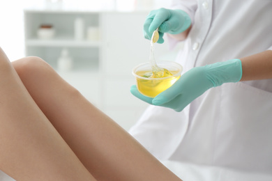 Woman getting wax epilation of legs in salon, closeup