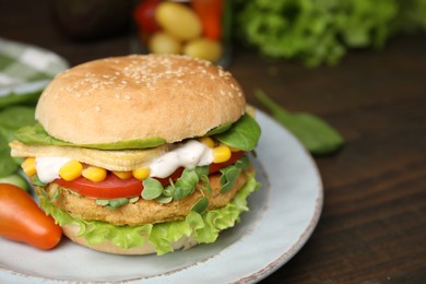 Photo of Tasty vegan burger with vegetables, patty and microgreens on wooden table, closeup. Space for text