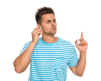 Emotional young man listening to music through wireless earphones on white background