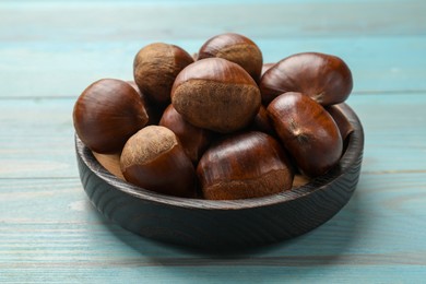 Roasted edible sweet chestnuts on light blue wooden table, closeup