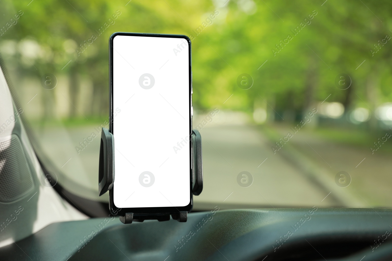 Photo of Car holder with modern mobile phone on windshield of automobile. Mockup for design