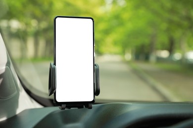 Photo of Car holder with modern mobile phone on windshield of automobile. Mockup for design