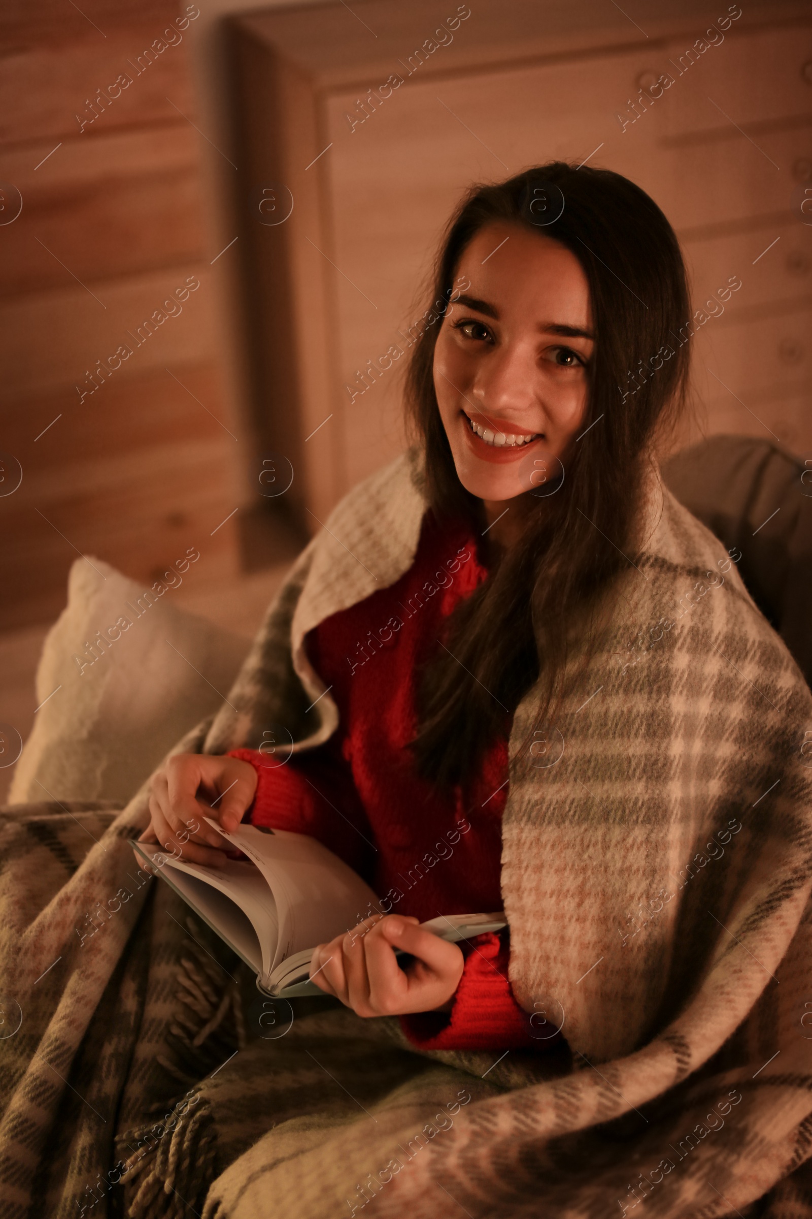 Photo of Woman with plaid reading book at home. Winter season