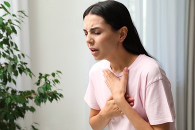 Photo of Young woman suffering from breathing problem indoors