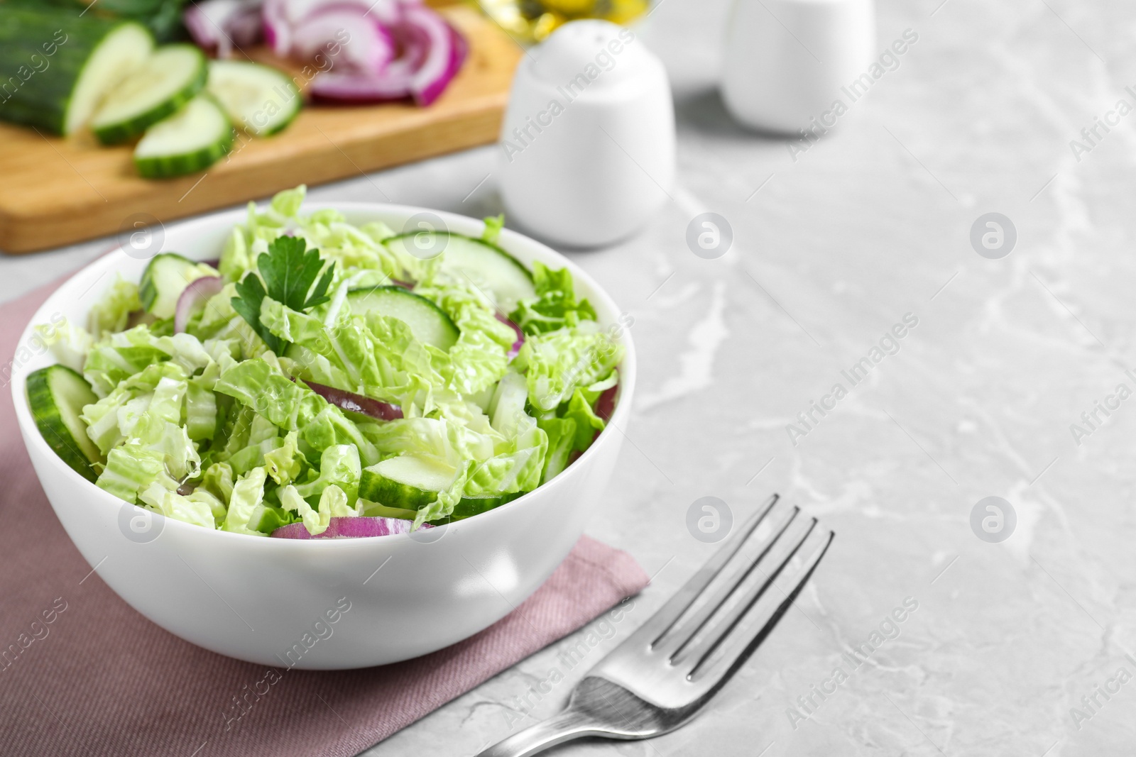 Photo of Tasty salad with cabbage and cucumbers on light grey marble table