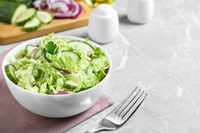 Photo of Tasty salad with cabbage and cucumbers on light grey marble table