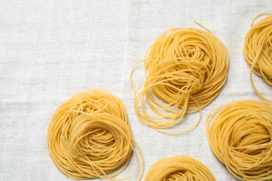 Photo of Capellini pasta on white tablecloth, flat lay