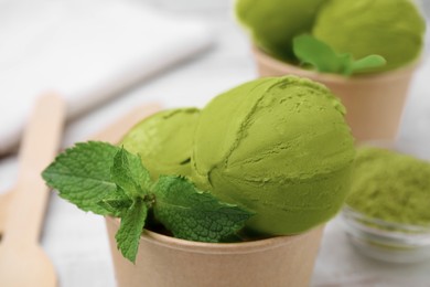 Photo of Paper cup with tasty matcha ice cream on table, closeup