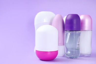 Composition with different female deodorants on purple background, space for text