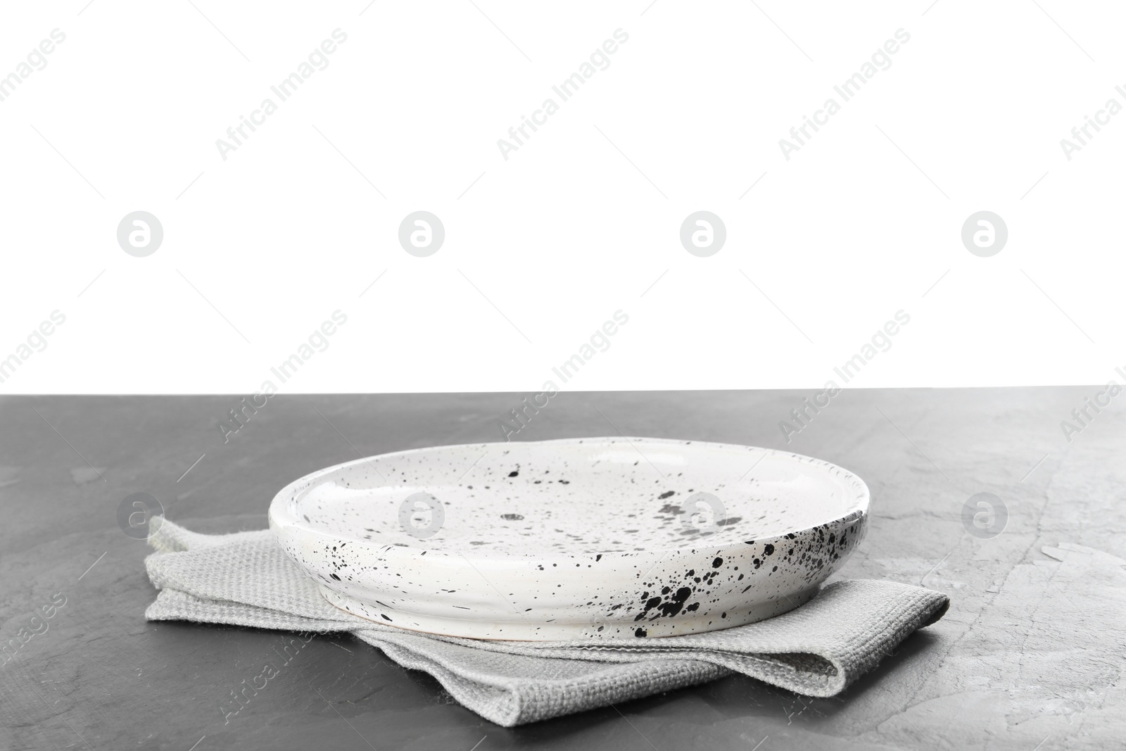 Photo of Empty patterned plate and napkin on black slate table against white background