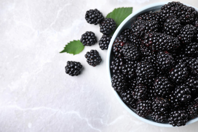 Photo of Fresh ripe blackberries in bowl on marble table, flat lay. Space for text