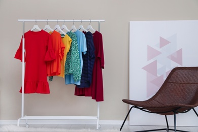 Photo of Wardrobe rack with colorful clothes in stylish room